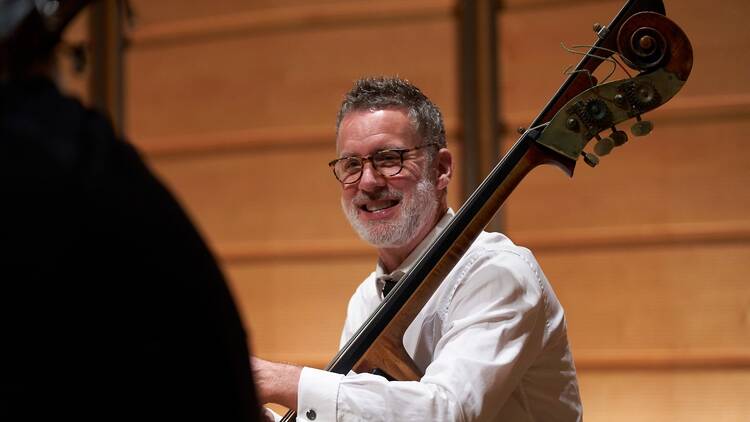 A smiling double bass player rehearsing with the Sydney Symphony Orchestra 