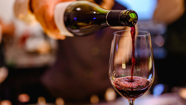 Pouring glass of red wine from a bottle.