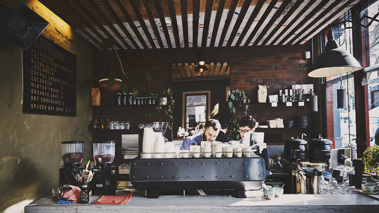 Baristas working behind the coffee machine at Collingwood's Plug Nickel café