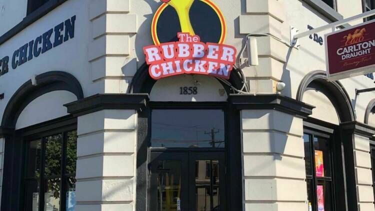 The outside of the Rubber Chicken, a comedy pub in South Melbourne. A large sign with a ribber chicken head hangs over the main entrance 