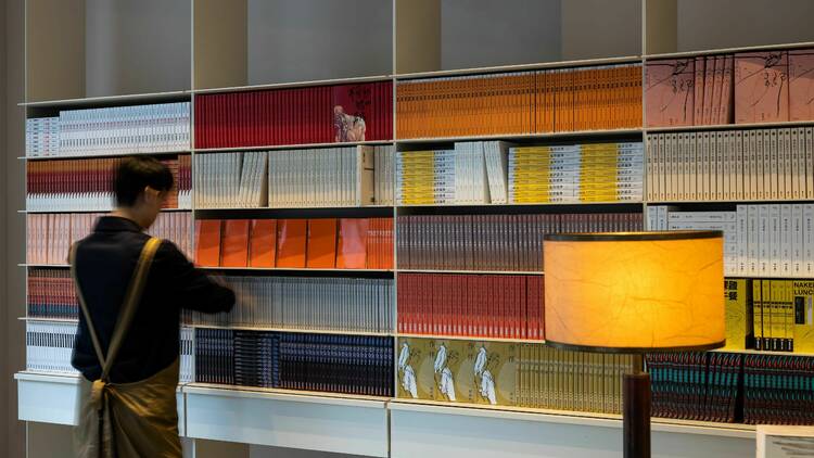 An employee at Aesop stocking shelves with LGBTQIA+ books for Aesop's Queer Library.