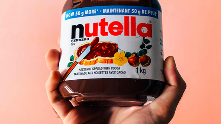 A hand holding a jar of Nutella spread.