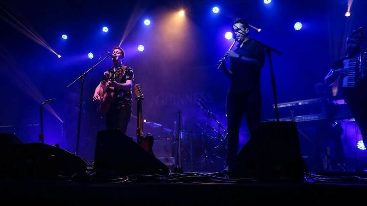 Two musicians performing on a dark stage