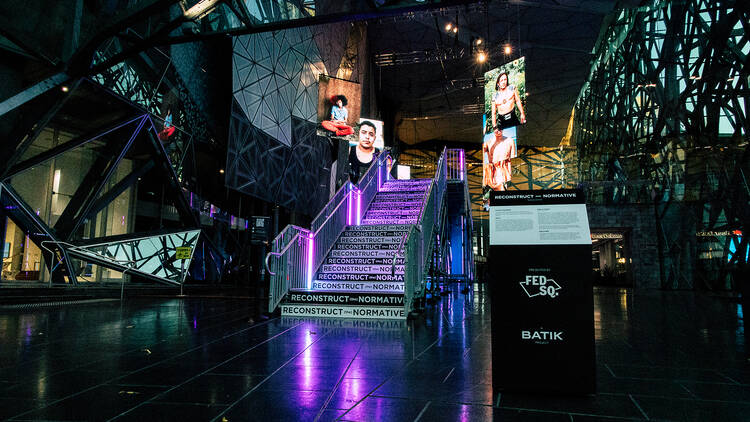 A bridge set up in Fed Square's atrium with Soraya Zaman's photos of trans men hanging on either side