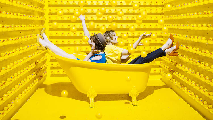 Two people sit in a yellow bathtub at Happy Place