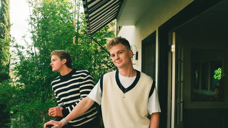 Two men standing on a balcony, members of the band Surfaces.