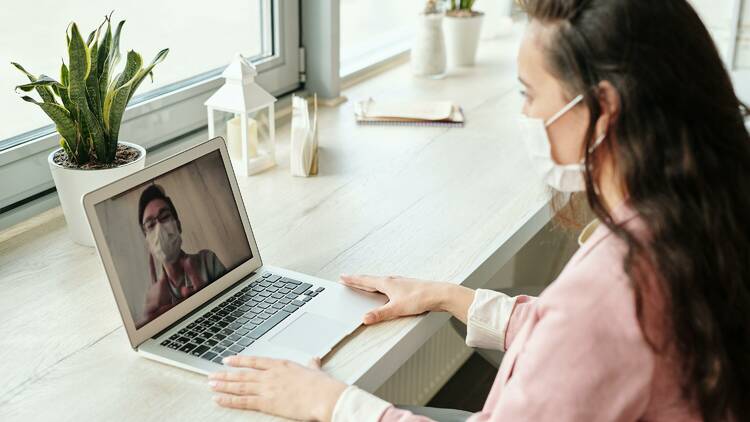 A woman in a face mask attends a Zoom meeting with a man in a face mask