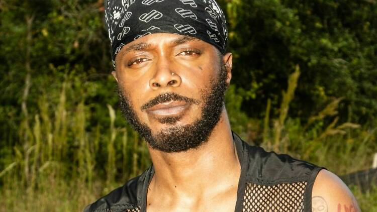 Musician Jpegmafia wearing a black bandana and a black mesh vest.