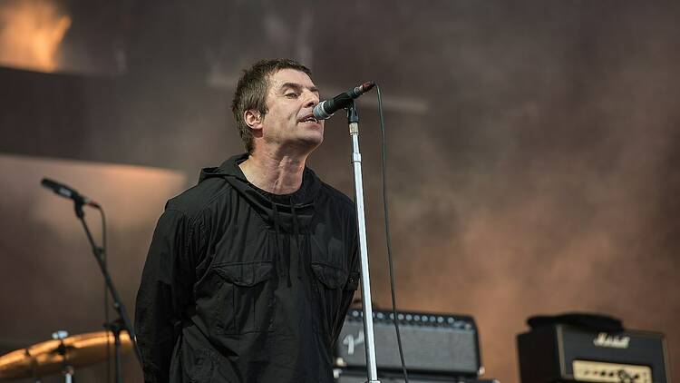 Singer Liam Gallagher standing at a mic on stage.
