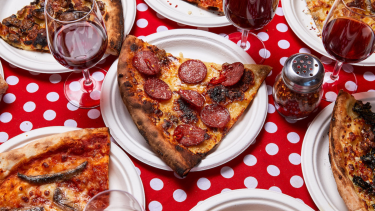 A flat lay of plates of pizza with wine glasses