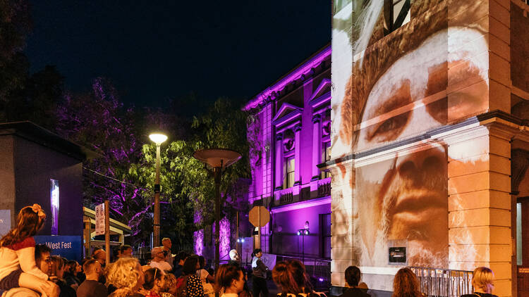 Ashfield town hall lit up with projections and a crowd observing