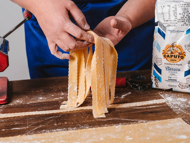 A person making pasta with a pasta machine.