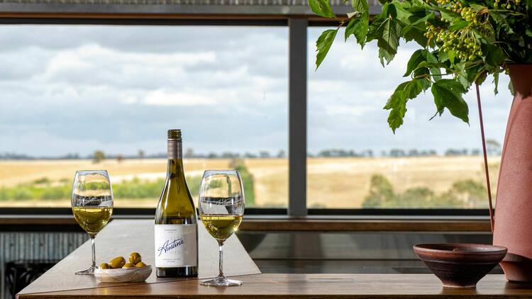 A bar countertop with a bottle of wine and two glasses.