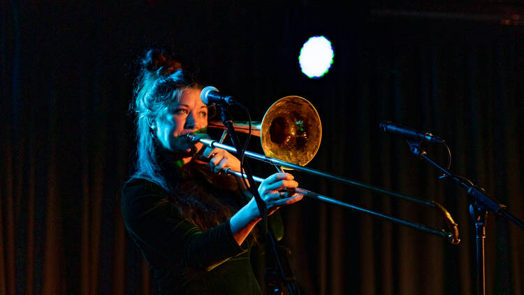 A woman plays the trombone on stage.