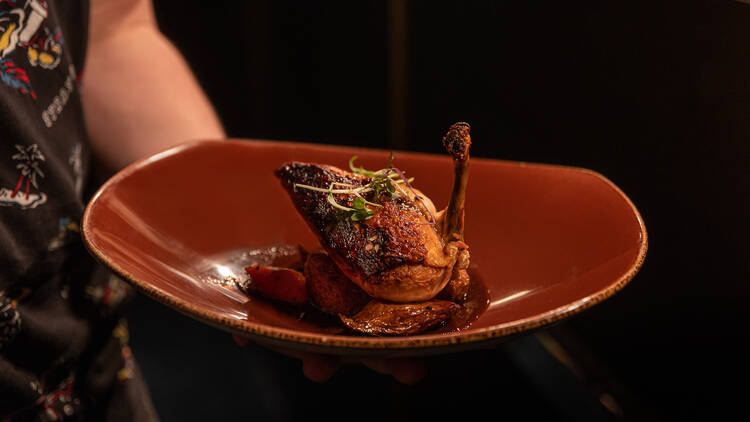 A brown plate with a chicken dish served on it.