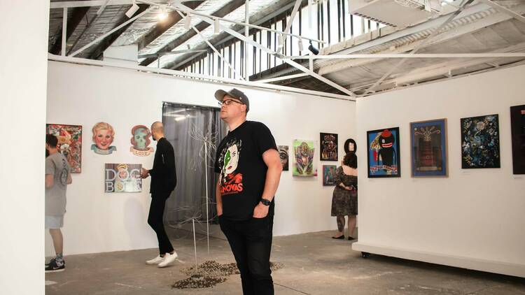 Individuals walking through an exhibition at Honey Bones Gallery.