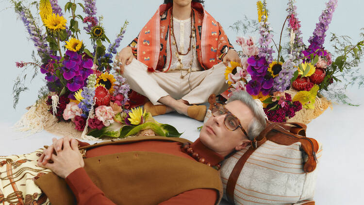 Client Liasion; Two men against a pale blue background with bouquets. 