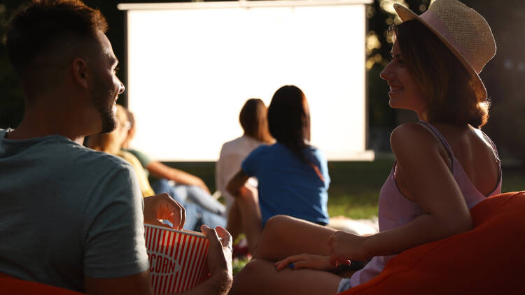 Young couple with popcorn watching a movie in an open-air cinema.