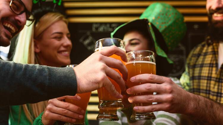 A group of friends cheers beers at a St Patrick's Day event