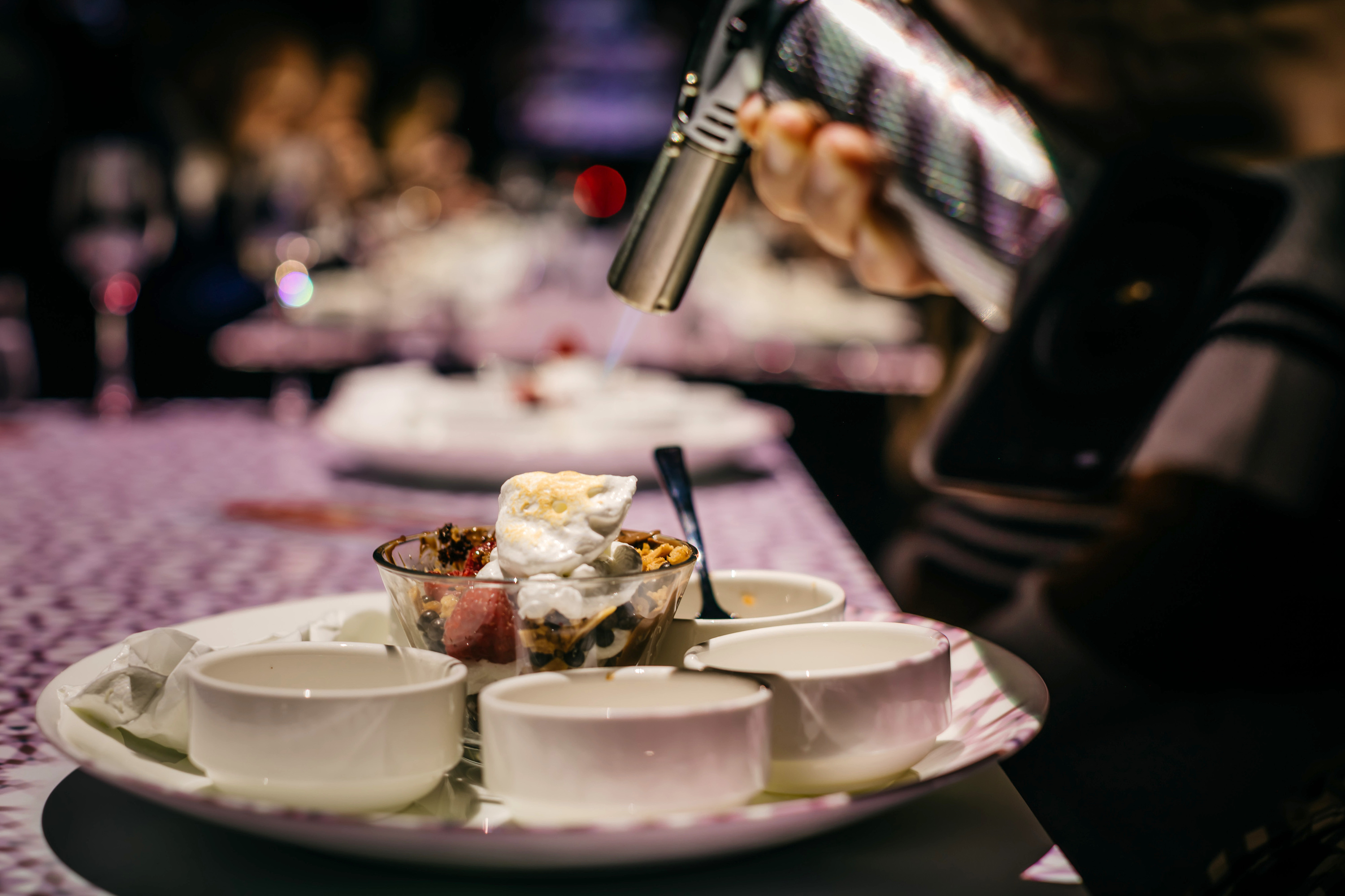 A server torches the marshmallow fluff atop Le Petit Chef's interactive dessert.