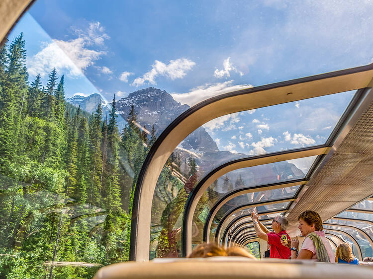 Rocky Mountaineer train traveling through the Rocky Mountains with luxury dining on board.