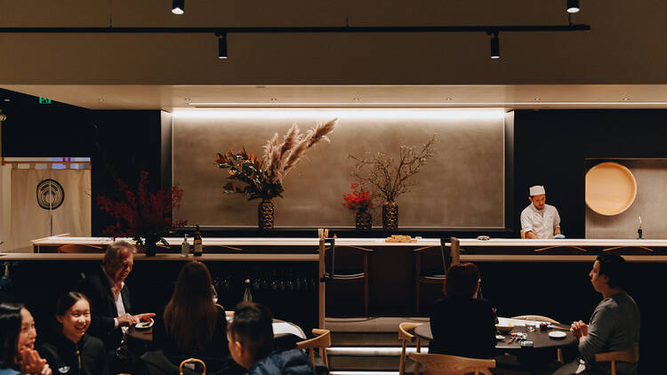 People dining inside of Komeyui as a sushi chef works in the background.