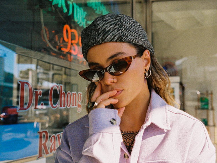 Singer and multi-instrumentalist Tash Sultana wearing a grey cap and brown cat eye sunglasses.