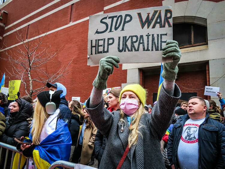 A group of protestors, one of whom is holding a sign that reads Stop War Help Ukraine.