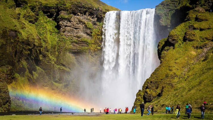24th August 2014, Skogafoss, Iceland: people admiring the beautiful and amazing Skogafoss waterfall with rainbow during a sunny summer day. That's one of the most famous icelandic falls