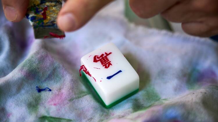 A craftsman painting a mahjong tile