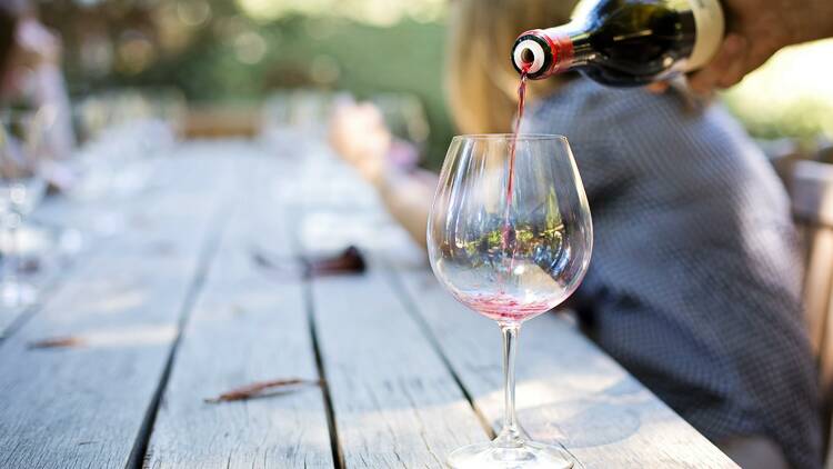 A bottle of red wine being poured into a glass.