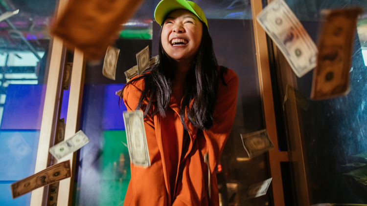 A woman laughing as she plays gold among flying US dollar bills