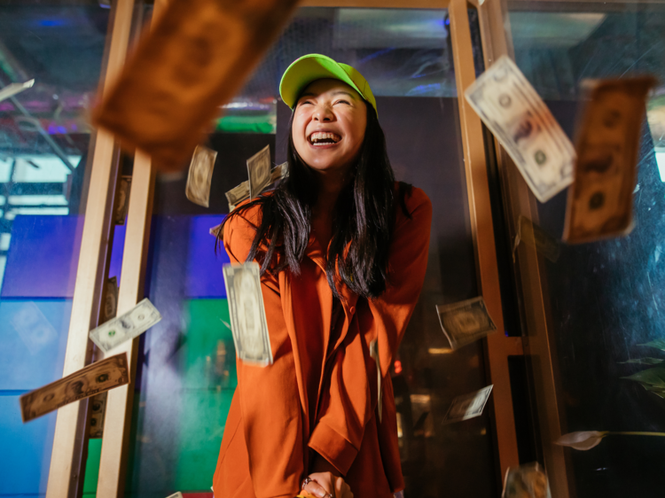 A woman laughing as she plays gold among flying US dollar bills