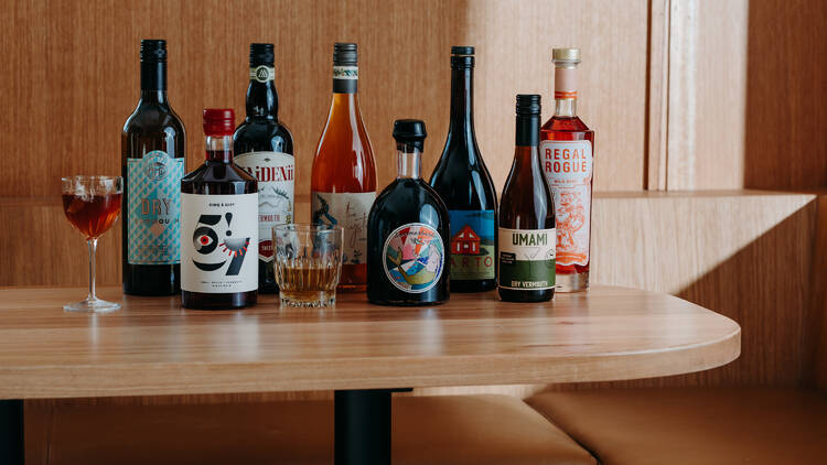 A group of liquors on a wooden table next to cocktails at Hotel Railway.
