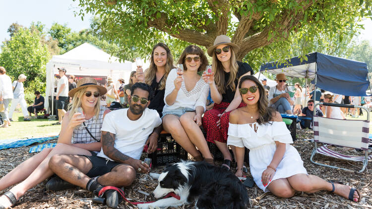 A group of friends sitting on the grass at East Malvern Food and Wine Festival.