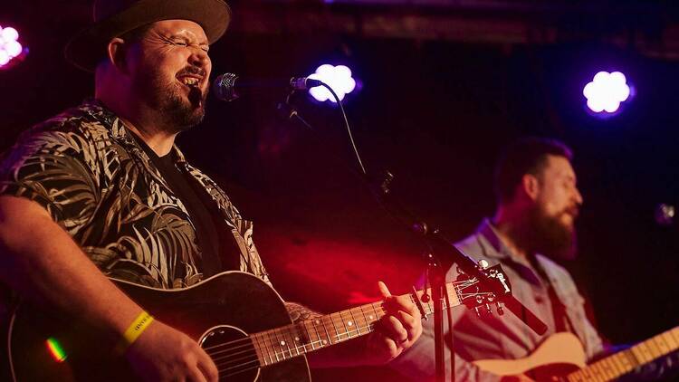 Musician Nathan Seeckts singing into a microphone on stage.