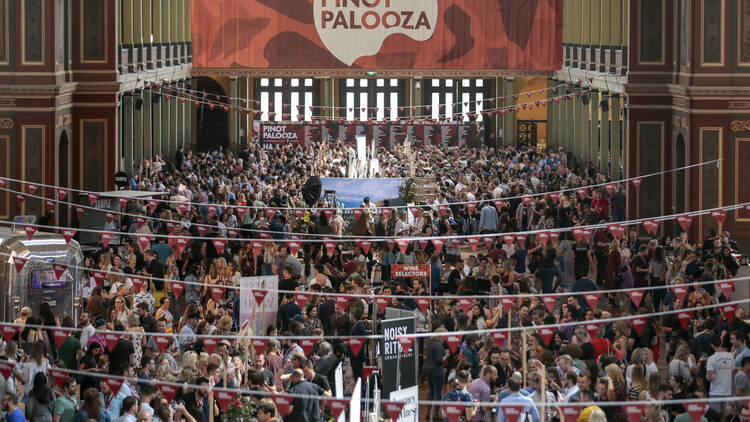 An aerial shot of a crowd of people inside of a building sipping wines at Pinot Palooza.