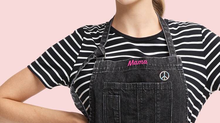 A woman wearing a black apron embroidered 'Mama'