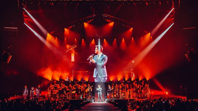 Michael Bublé performs in a grey suit with red lighting