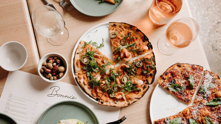A platter of sliced pizza atop a menu that reads Bonnie.