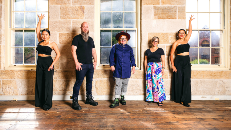 A group of people stand in a room with sandstone walls