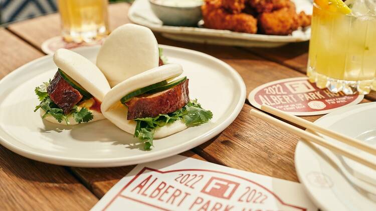 A table set with bao buns, chicken wings and cocktails for an F1 pop-up.