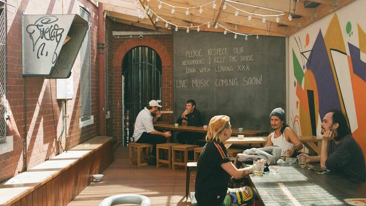 A beer garden with people sitting at long benches.