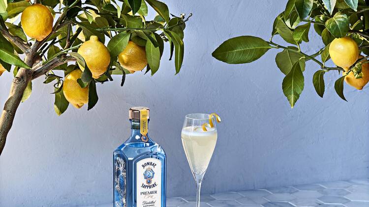 A bottle of Bombay Sapphire Premier Cru with a cocktail served with a lemon garnish.