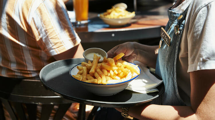 A waiter holding a tray with a bowl of chips.
