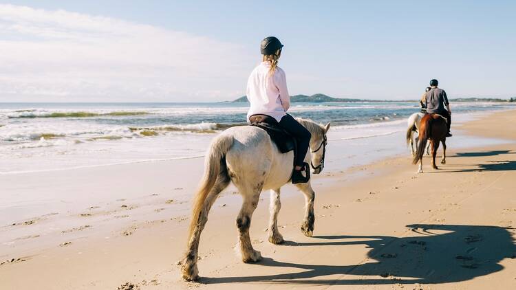 Group enjoying a horse-riding experience along Tyagarah Beach with Zephryr Horses in Byron Bay