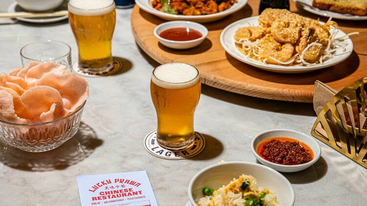 A spread of ice-cold beers and plates of Chinese food – included prawn crackers and fried rice – on a stone table.