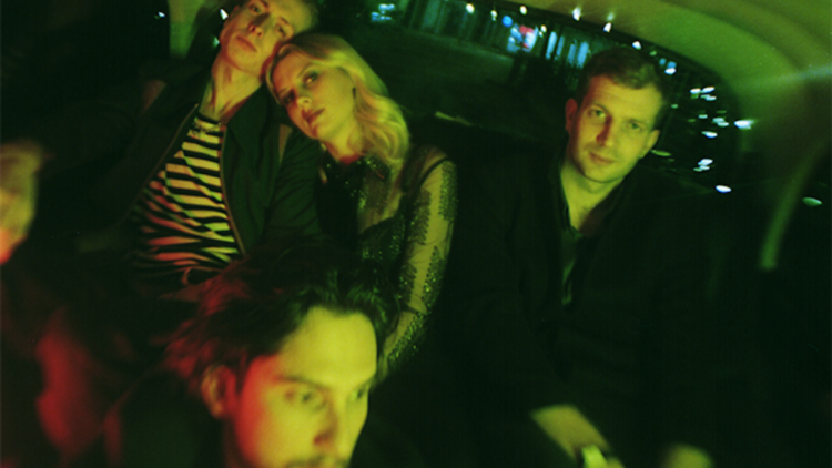 The band wolf alice sitting in the back of a car.