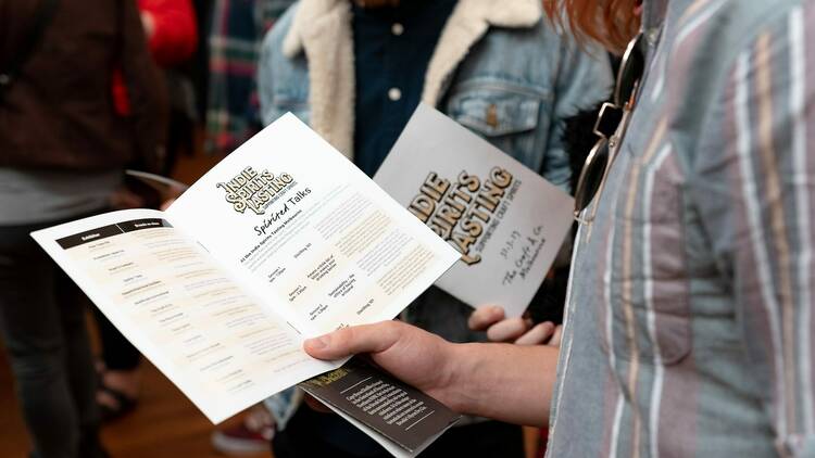 People browsing a pamphlet on Indie Spirits Tasting.