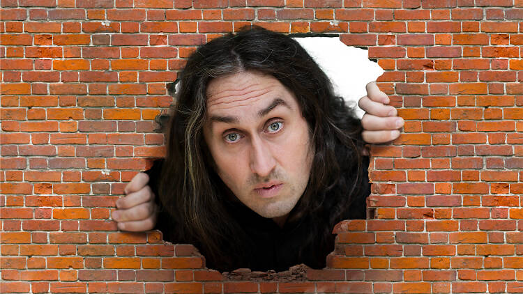 Ross Noble peeks through a brick wall